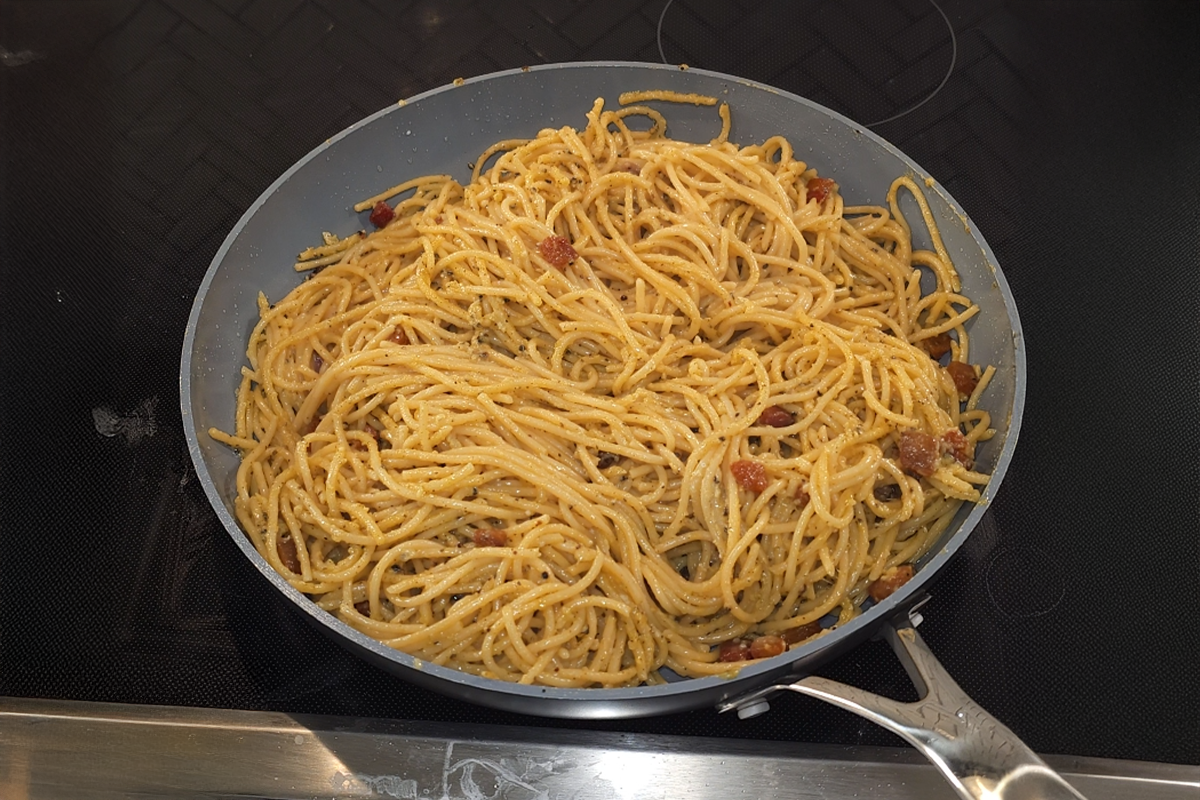 Creamy spaghetti carbonara tossed with crispy guanciale in a skillet, coated in a silky sauce of egg, Parmigiano Reggiano, and Pecorino Romano.